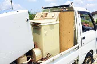 軽トラックの荷台に積まれた古い洗濯機や家電製品