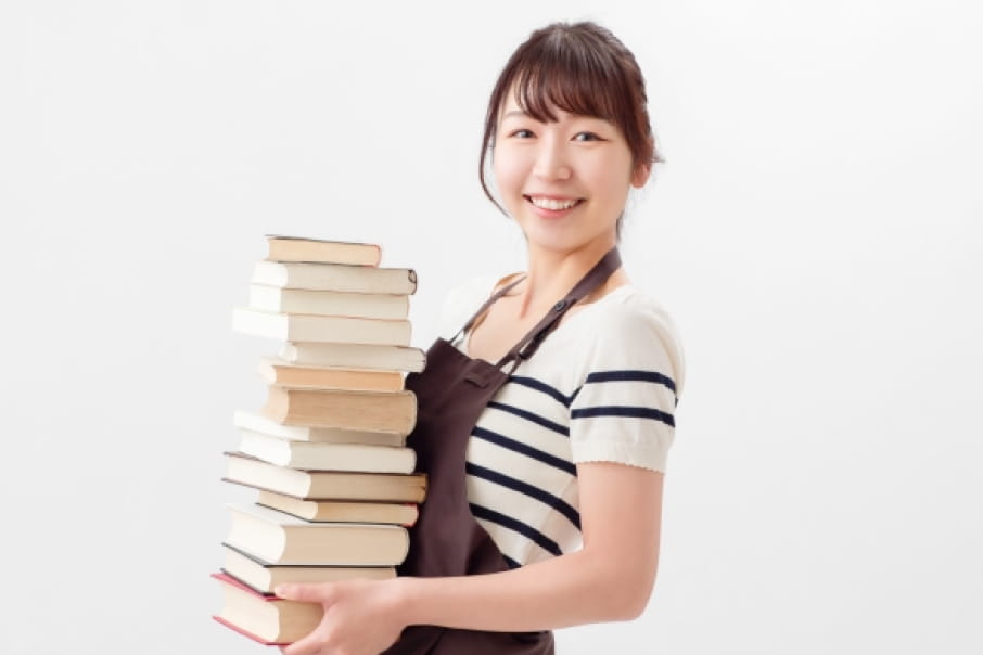 書店や図書館のスタッフのような雰囲気の女性が、本を運んでいる様子。